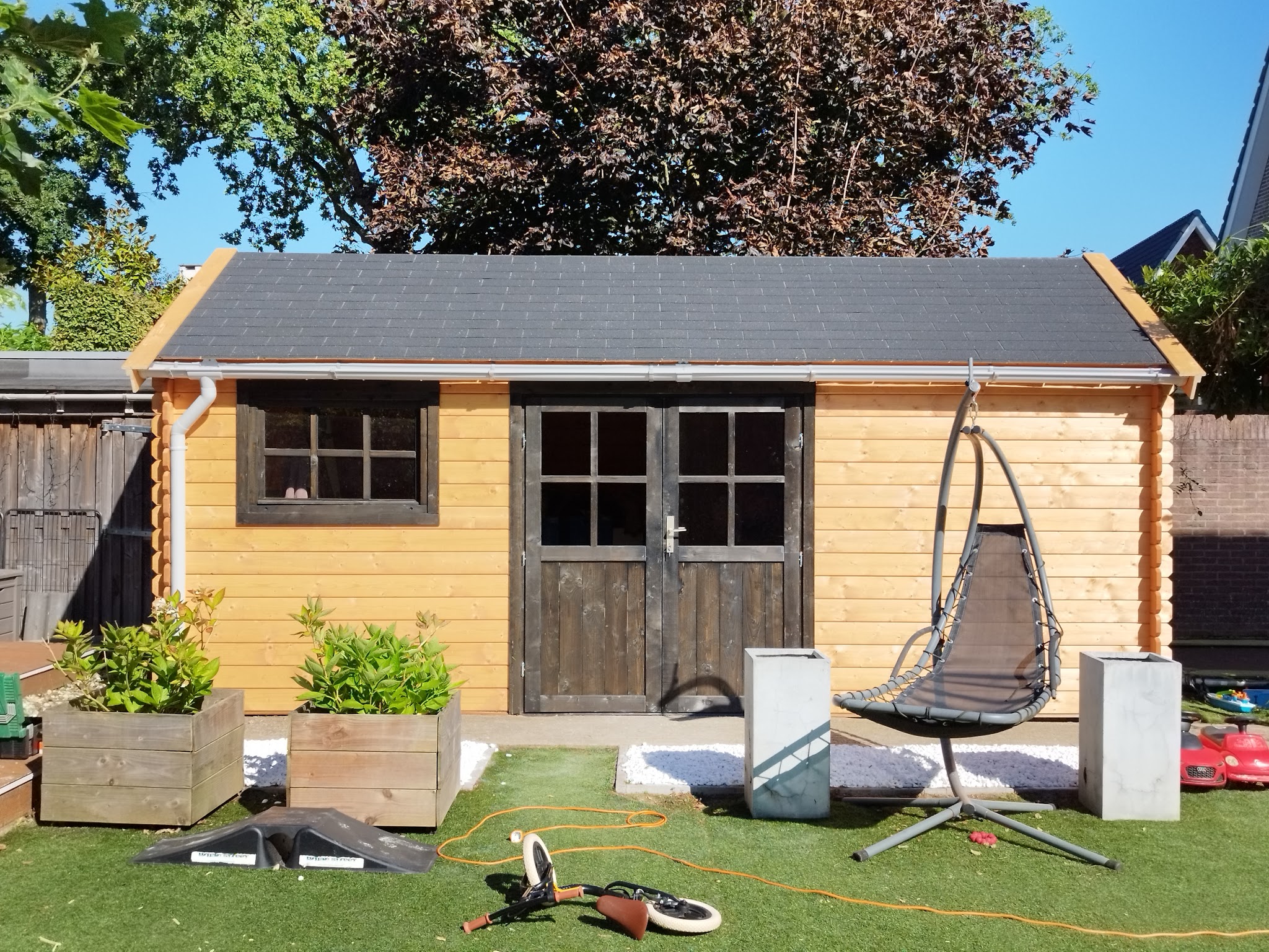 Houten tuinhuis met dubbele deuren in een achtertuin