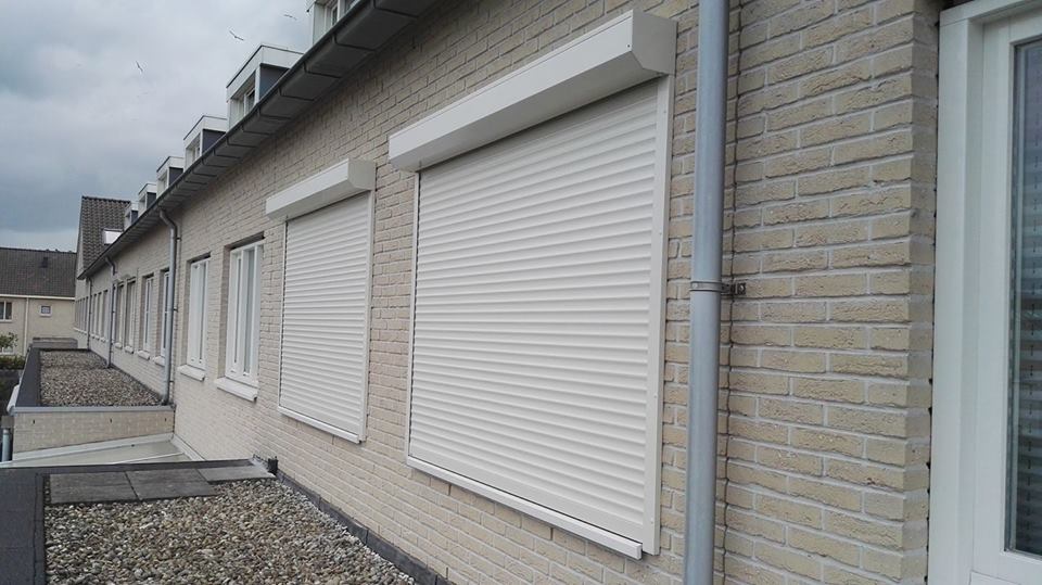 Twee witte rolluiken gemonteerd aan de gevel van een rijtjeshuis